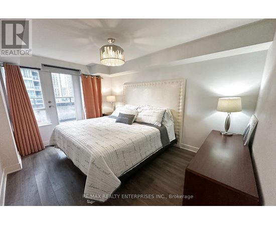 A bedroom with a large bed and a chandelier.