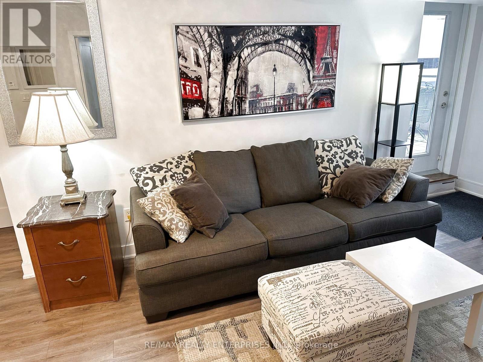 A living room with a grey couch, a white coffee table, and a painting on the wall.