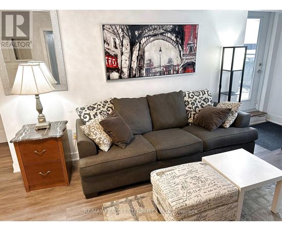 A living room with a grey couch, a white coffee table, and a painting on the wall.