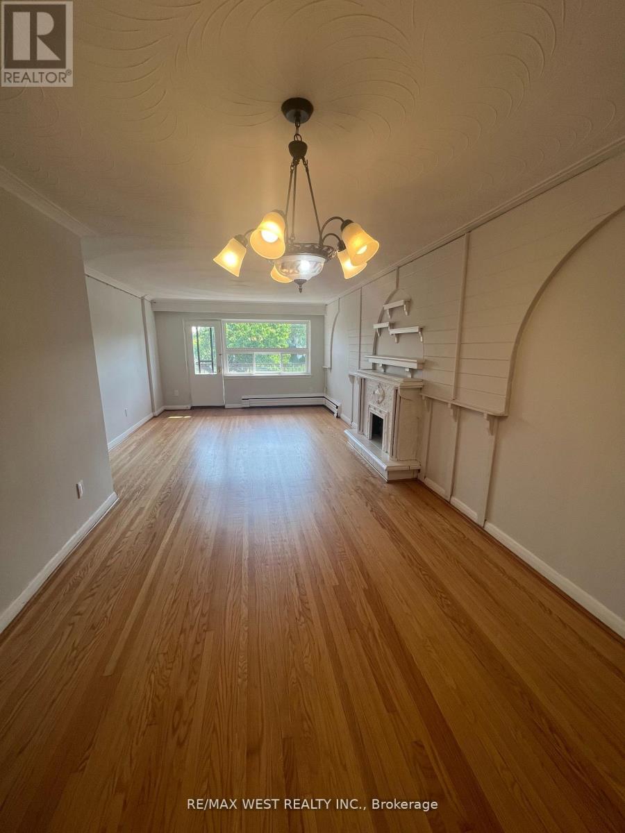 A long hallway with wood floors and a light hanging from the ceiling.