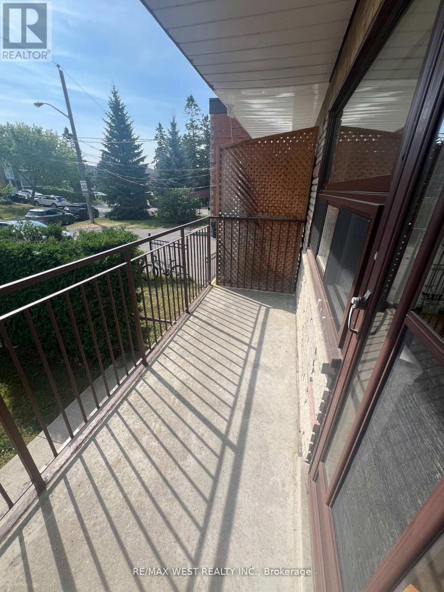 A balcony with a metal railing and a view of a street and trees.
