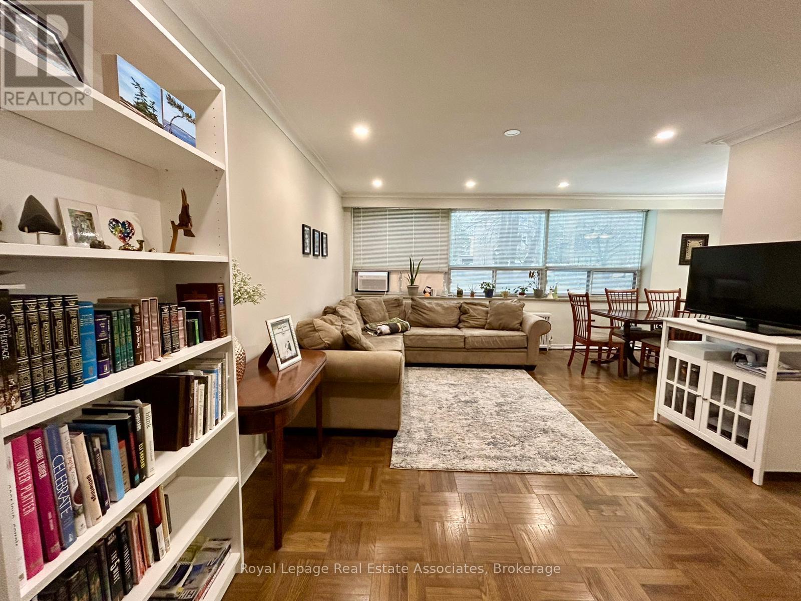 A living room with a couch, a coffee table, a bookshelf, and a television.
