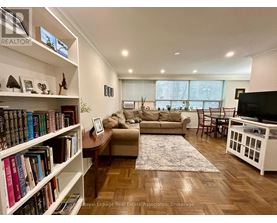 A living room with a couch, a coffee table, a bookshelf, and a television.