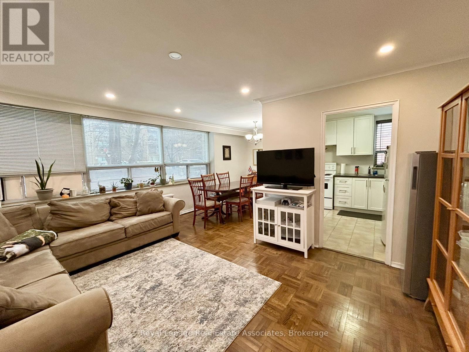 A living room with a couch, chairs, and a television.