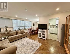 A living room with a couch, chairs, and a television.