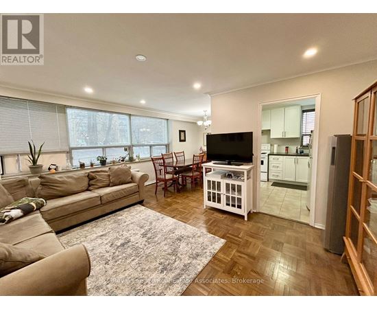 A living room with a couch, chairs, and a television.