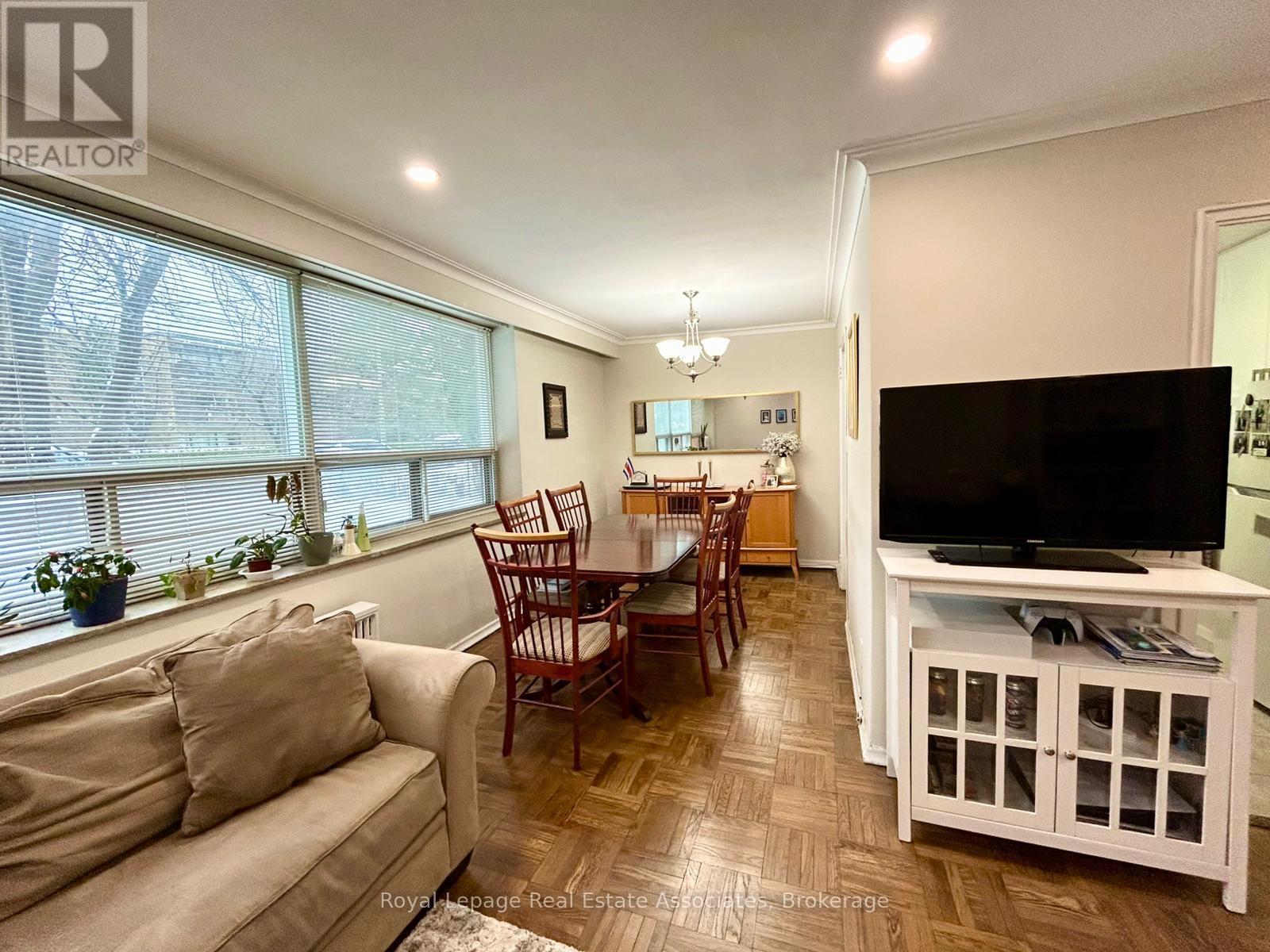 A living room with a couch, chairs, and a television.