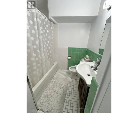 A white sink in a green tiled bathroom.