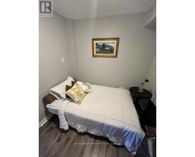 A bedroom with a bed, a small table with a flower vase, and a painting on the wall.