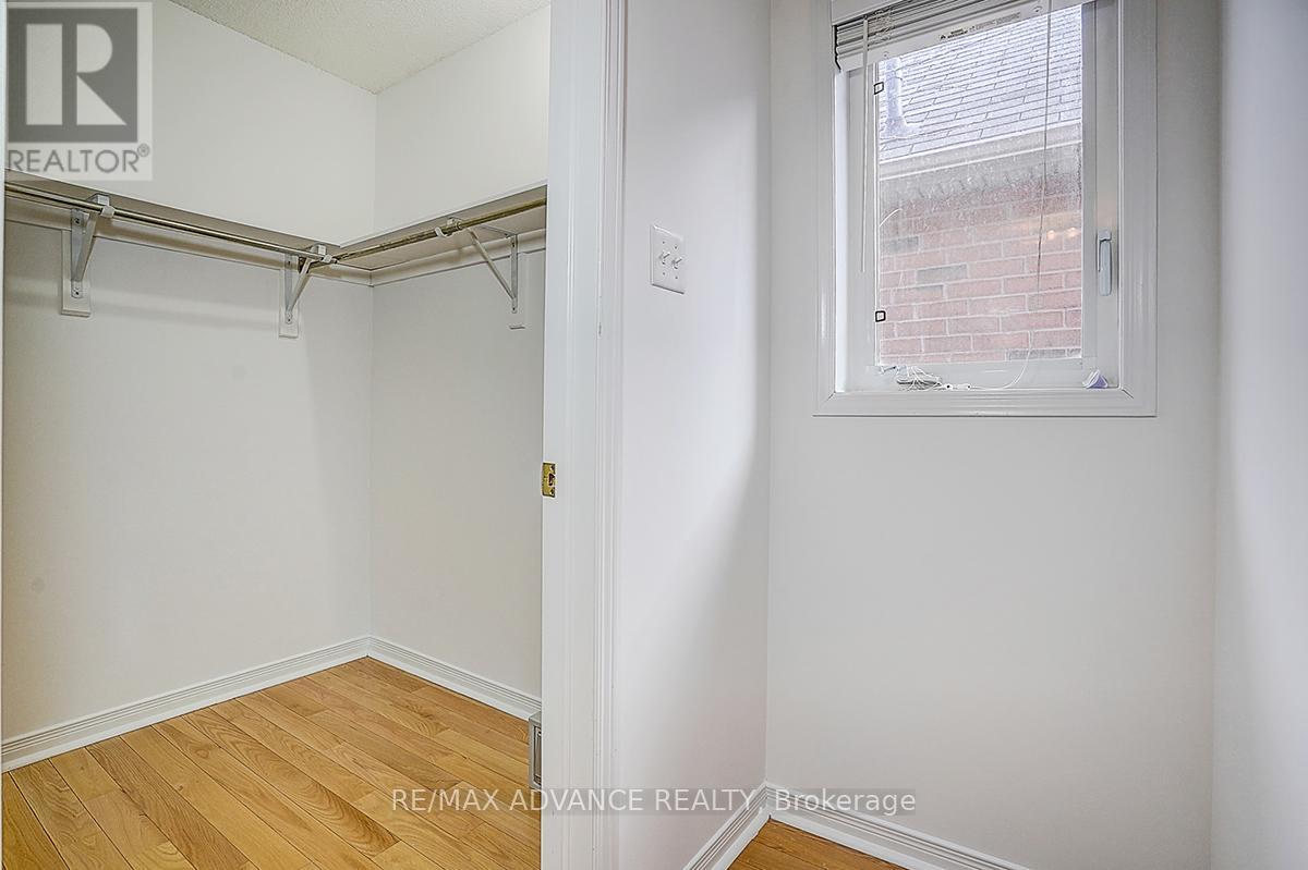 A white bedroom with a window and a wooden floor.