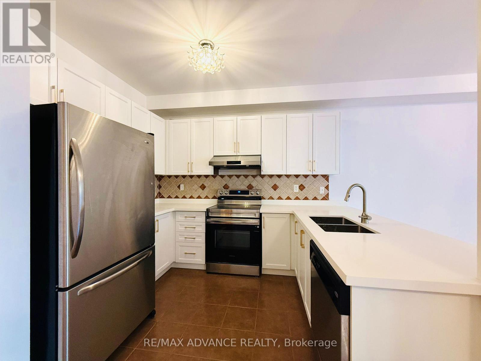 A modern kitchen with a stainless steel refrigerator and white cabinets.