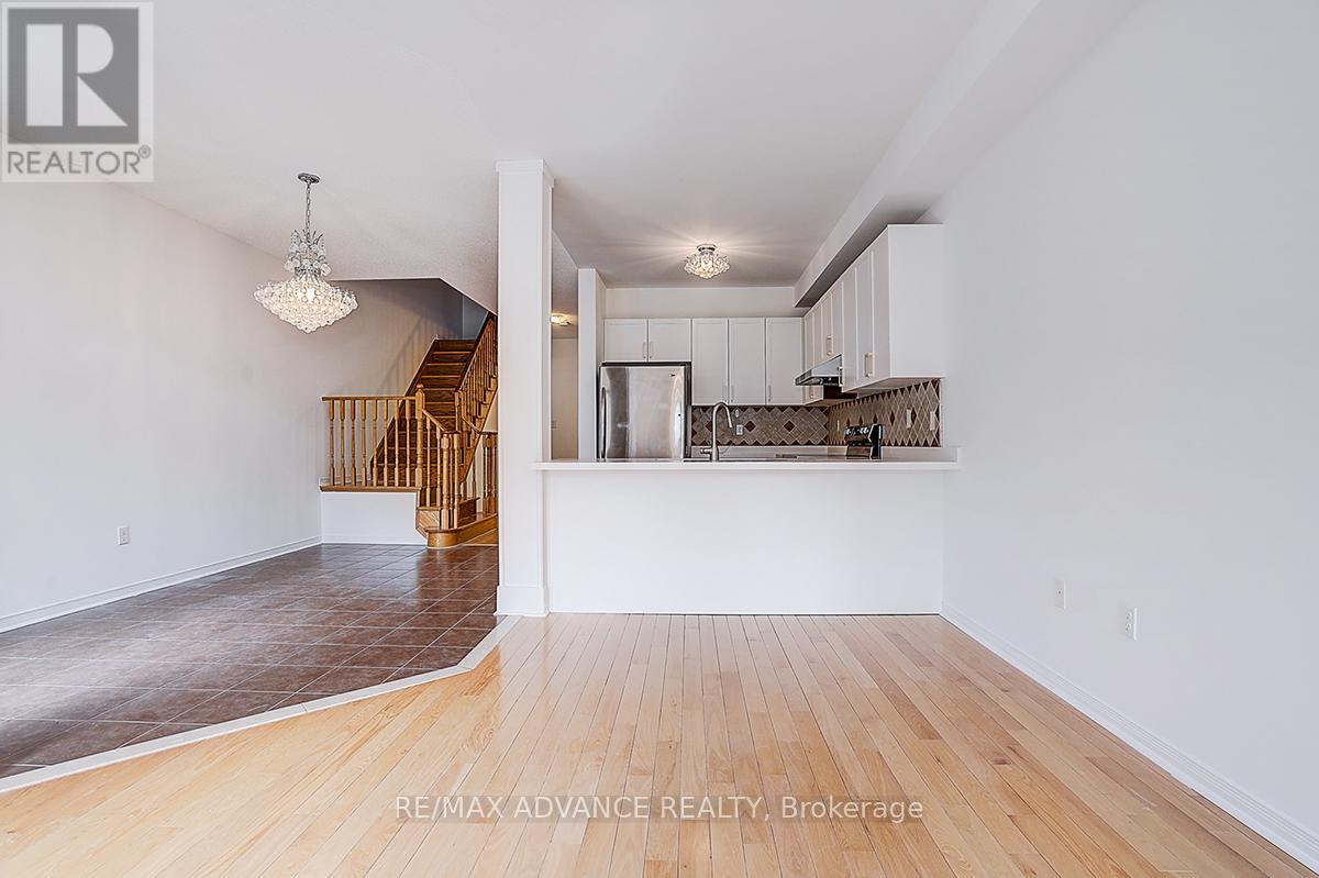 A spacious room with wooden flooring and white walls, featuring a doorway leading to another room.