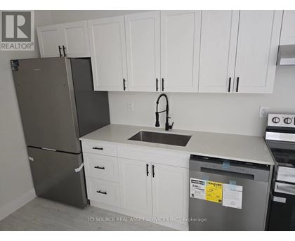 A kitchen with white cabinets and a black refrigerator.