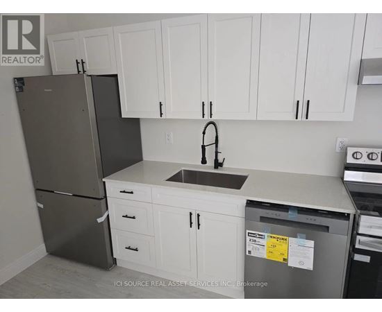 A kitchen with white cabinets and a black refrigerator.
