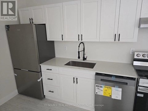 A kitchen with white cabinets and a black refrigerator.