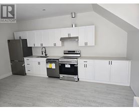 A kitchen with white cabinets and a black fridge.