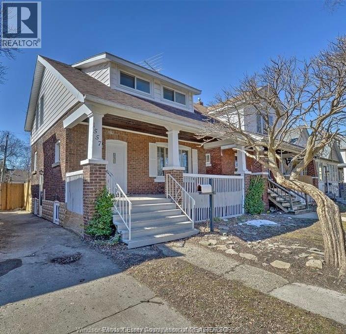 A house with a white porch and a brown roof is for sale.