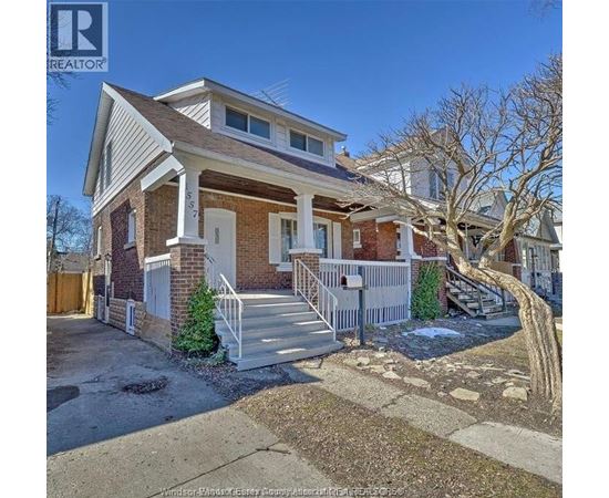 A house with a white porch and a brown roof is for sale.