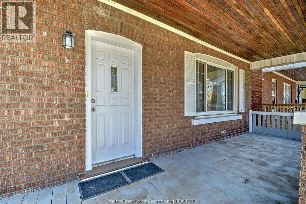 A white door is on the left side of a brick house.