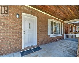 A white door is on the left side of a brick house.