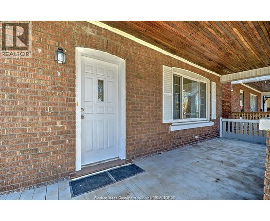 A white door is on the left side of a brick house.