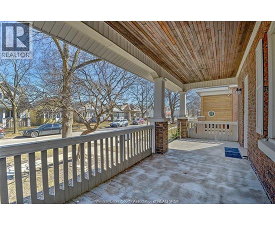 A porch with a wooden ceiling and a brick pillar.