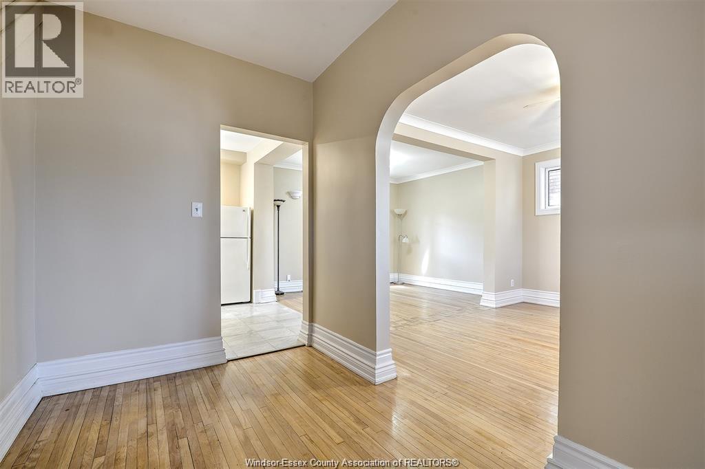 A spacious room with wooden floors and a large archway leading to another room.