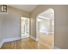 A spacious room with wooden floors and a large archway leading to another room.