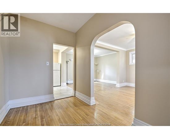 A spacious room with wooden floors and a large archway leading to another room.