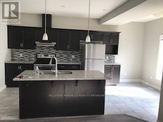 A modern kitchen with a black countertop and a stainless steel refrigerator.