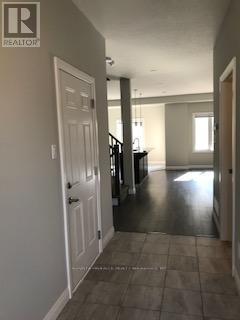 A hallway with a white door on the left and a black staircase on the right.
