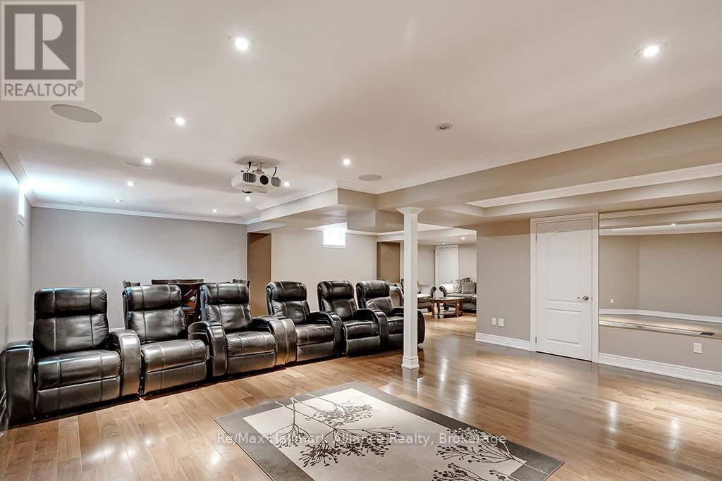 A living room with a row of black leather chairs facing a television.