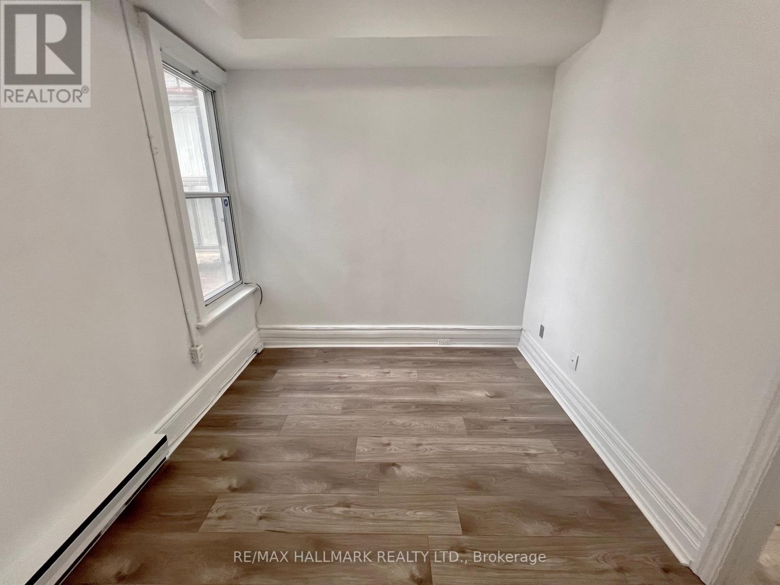 A room with wooden flooring and white walls.