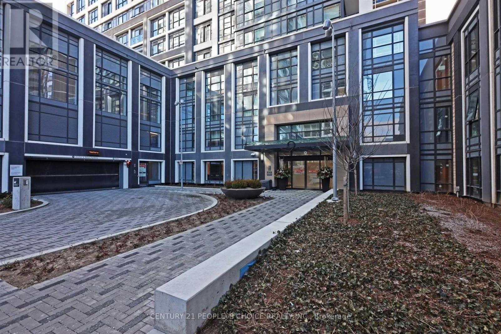 A modern building with glass windows and a brick walkway in front.