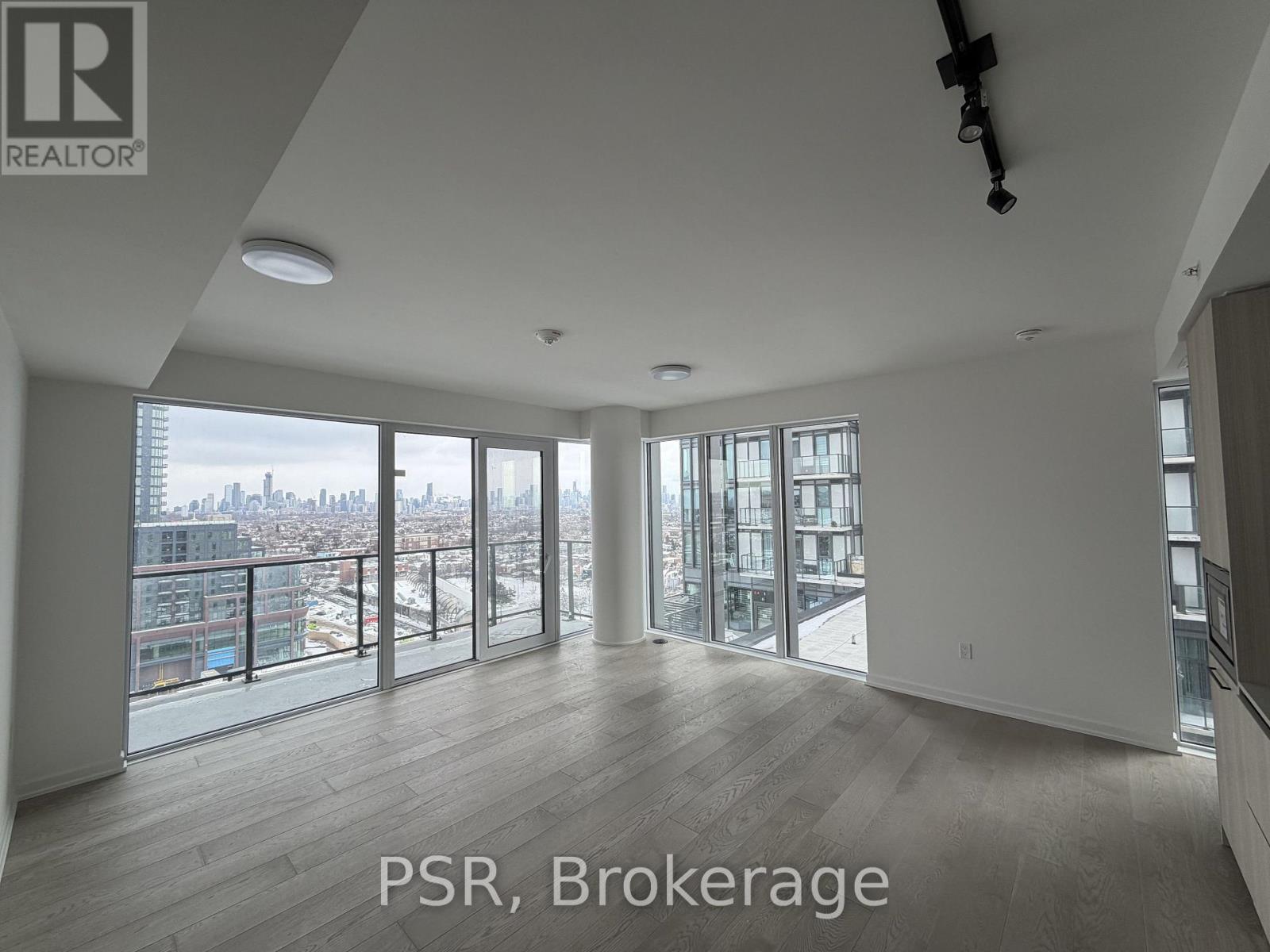 A spacious room with a view of the cityscape through large windows.