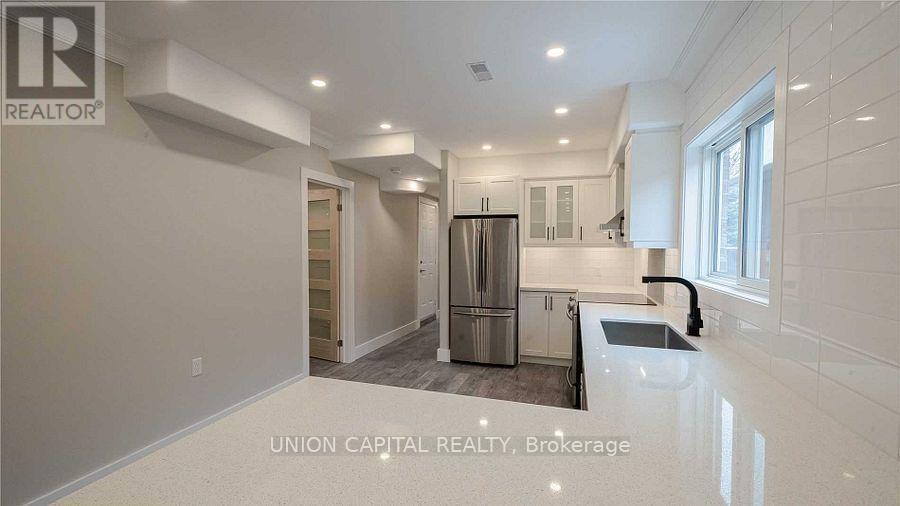 A kitchen with a refrigerator, sink, and cabinets.
