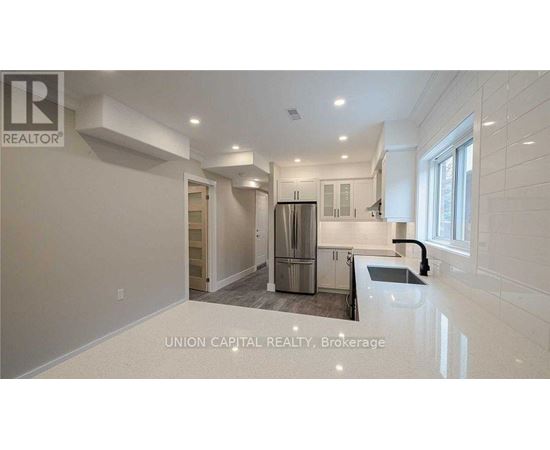 A kitchen with a refrigerator, sink, and cabinets.