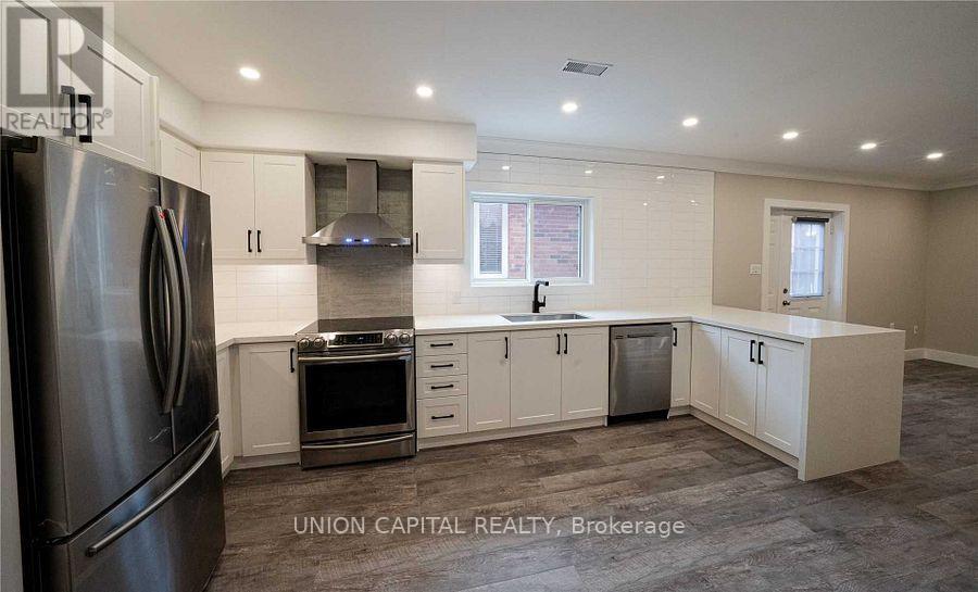 A kitchen with a refrigerator, oven, and cabinets.