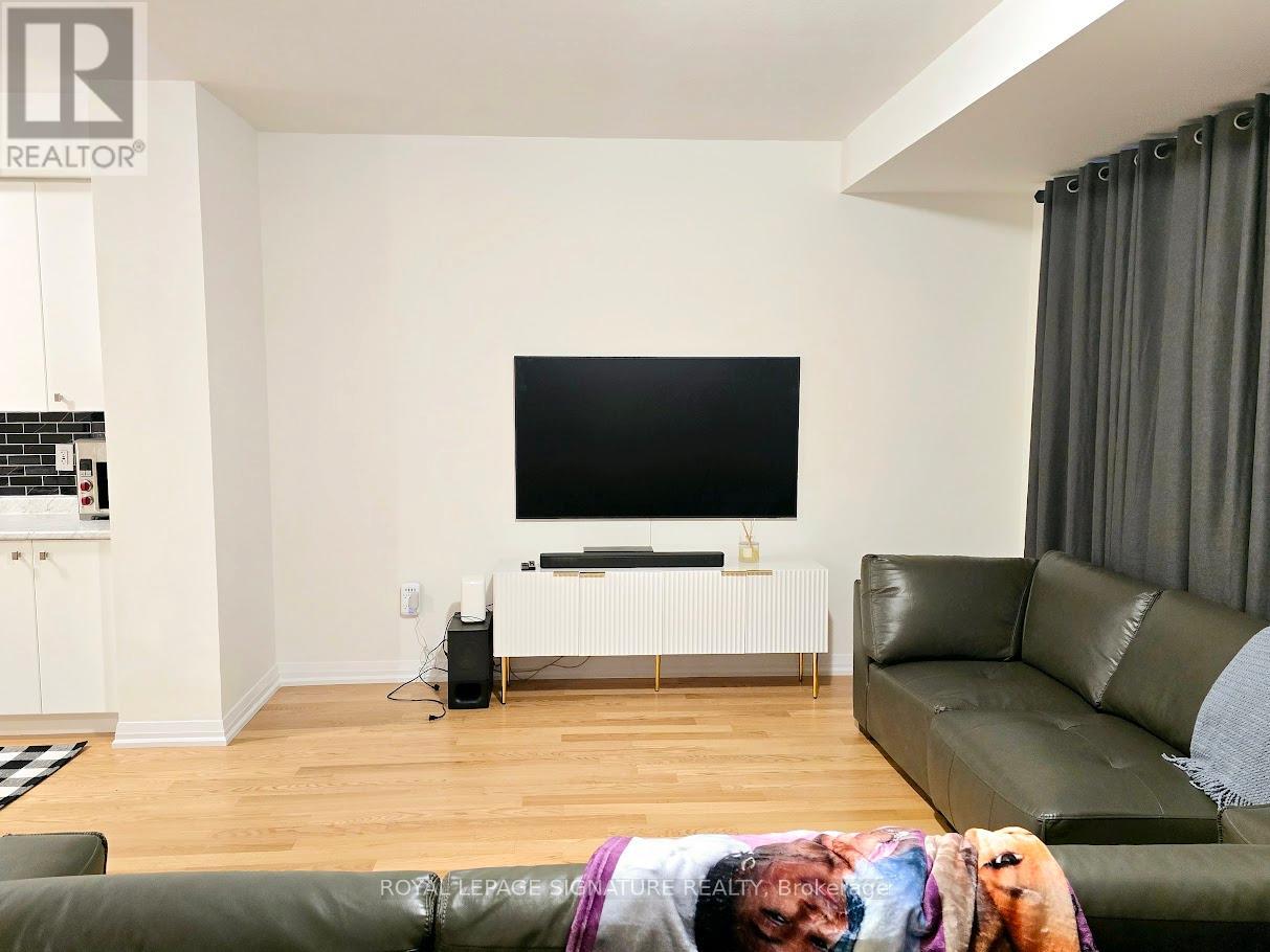 A living room with a green couch and a flat screen TV mounted on the wall.