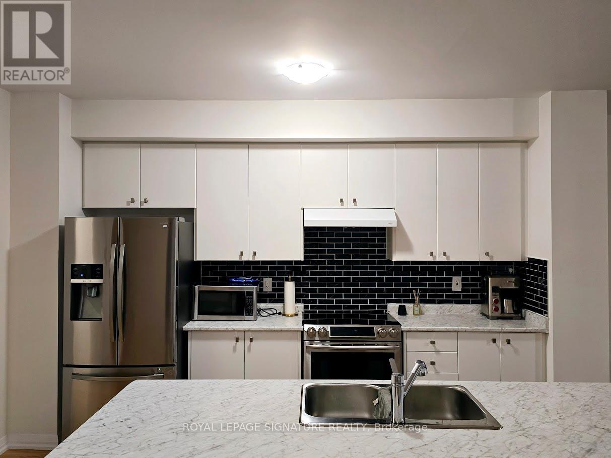A kitchen with white cabinets and a black backsplash.