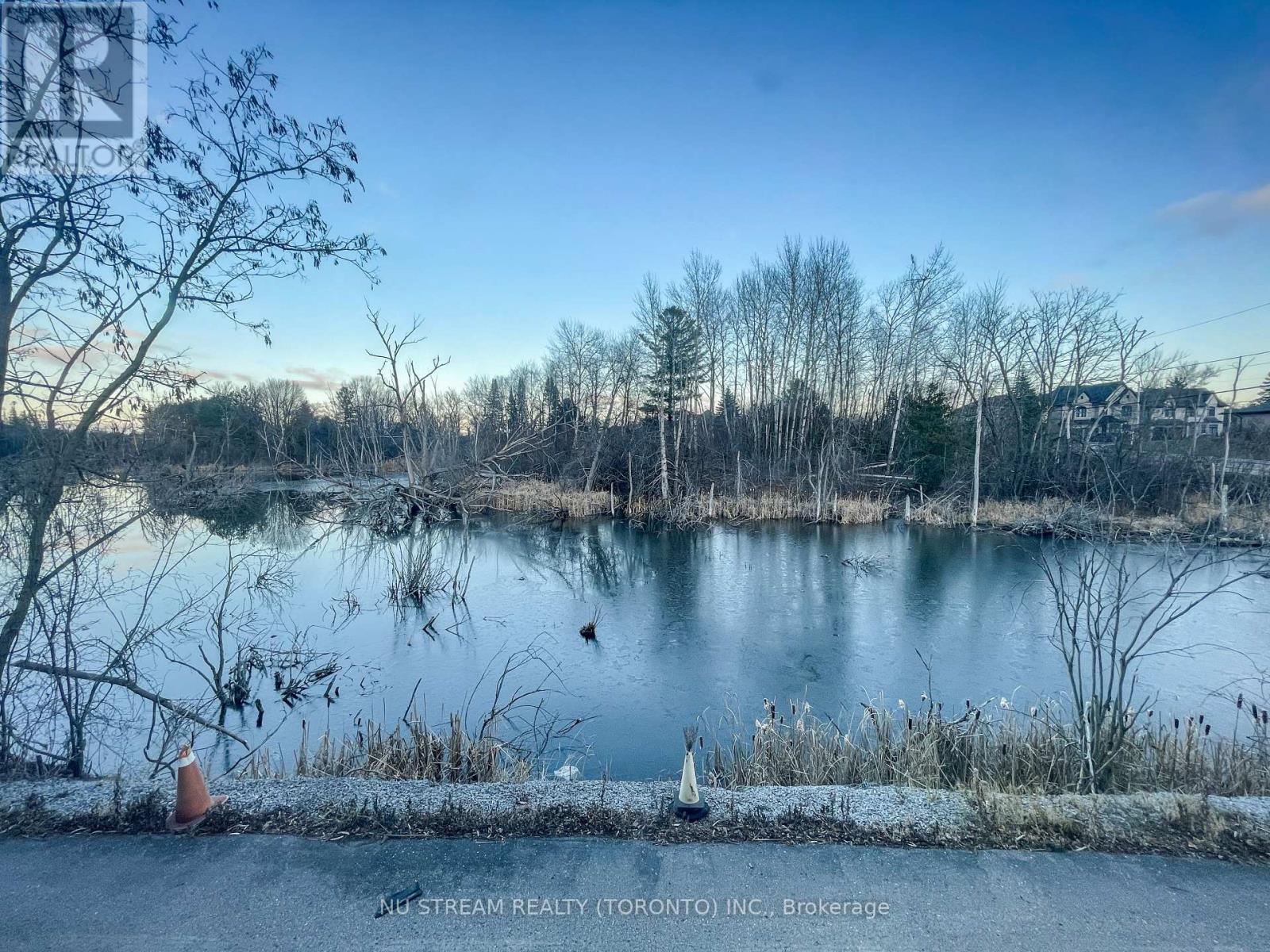 A serene lake surrounded by trees and a clear sky.