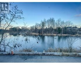A serene lake surrounded by trees and a clear sky.