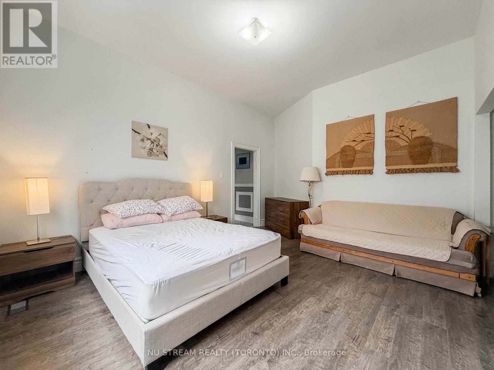 A bedroom with a large bed and a sofa.