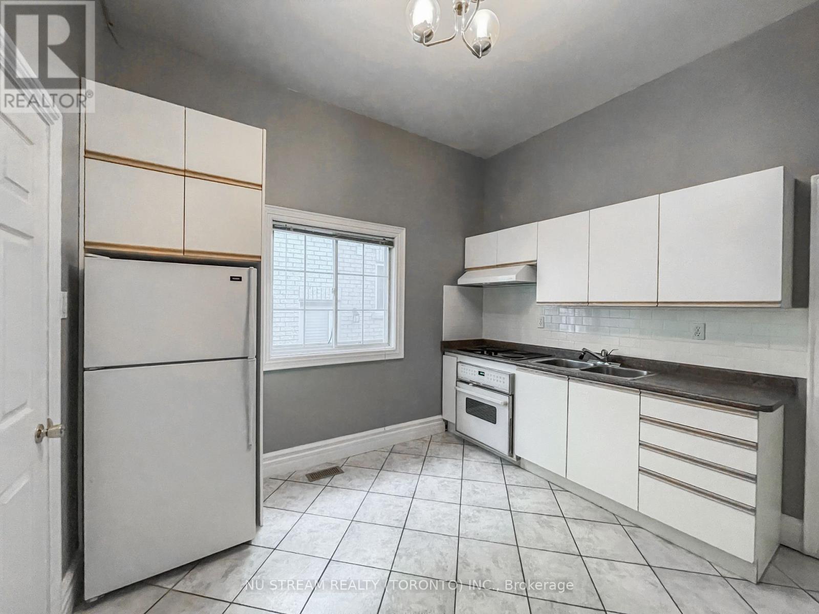 A kitchen with white cabinets and a white refrigerator.