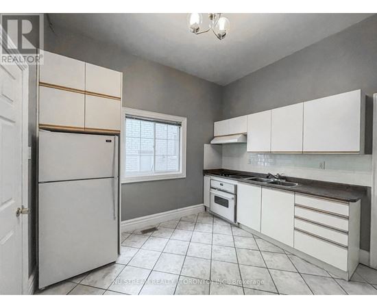 A kitchen with white cabinets and a white refrigerator.