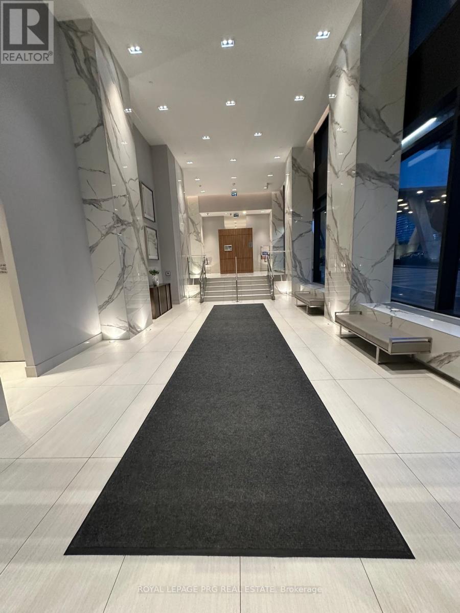 A hallway with a black carpet leading to a door.