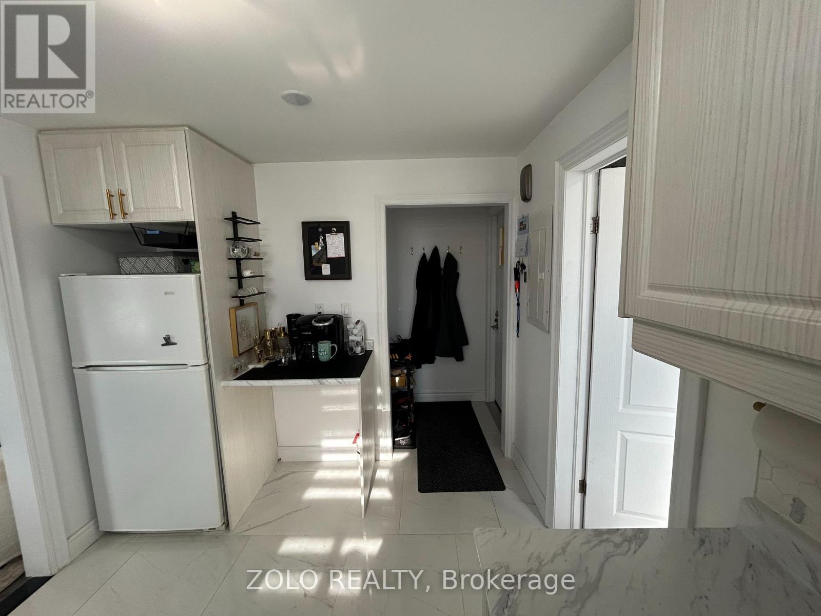 A kitchen with a white fridge and a black mat on the floor.