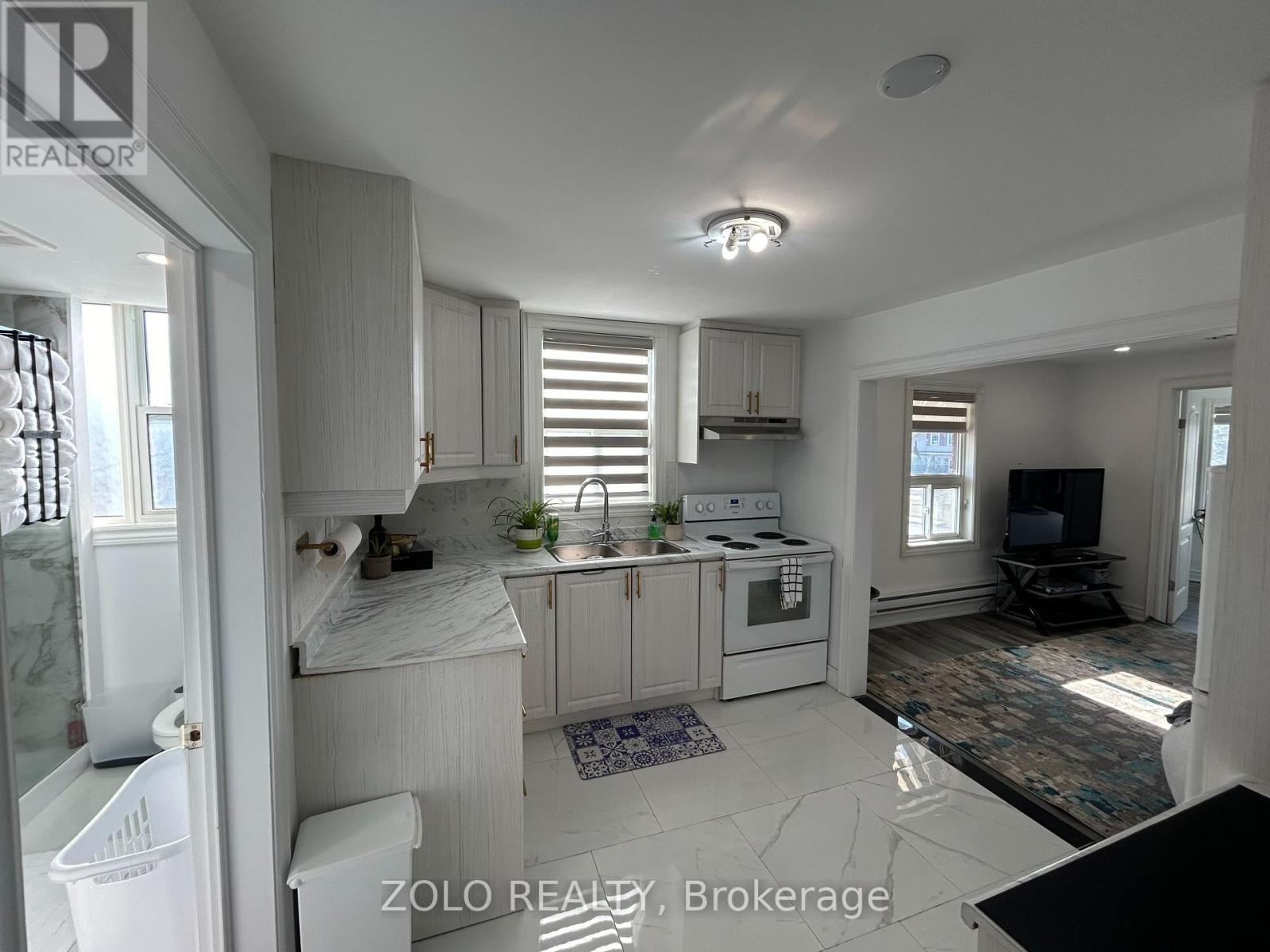 A modern kitchen with white cabinets and a marble countertop.