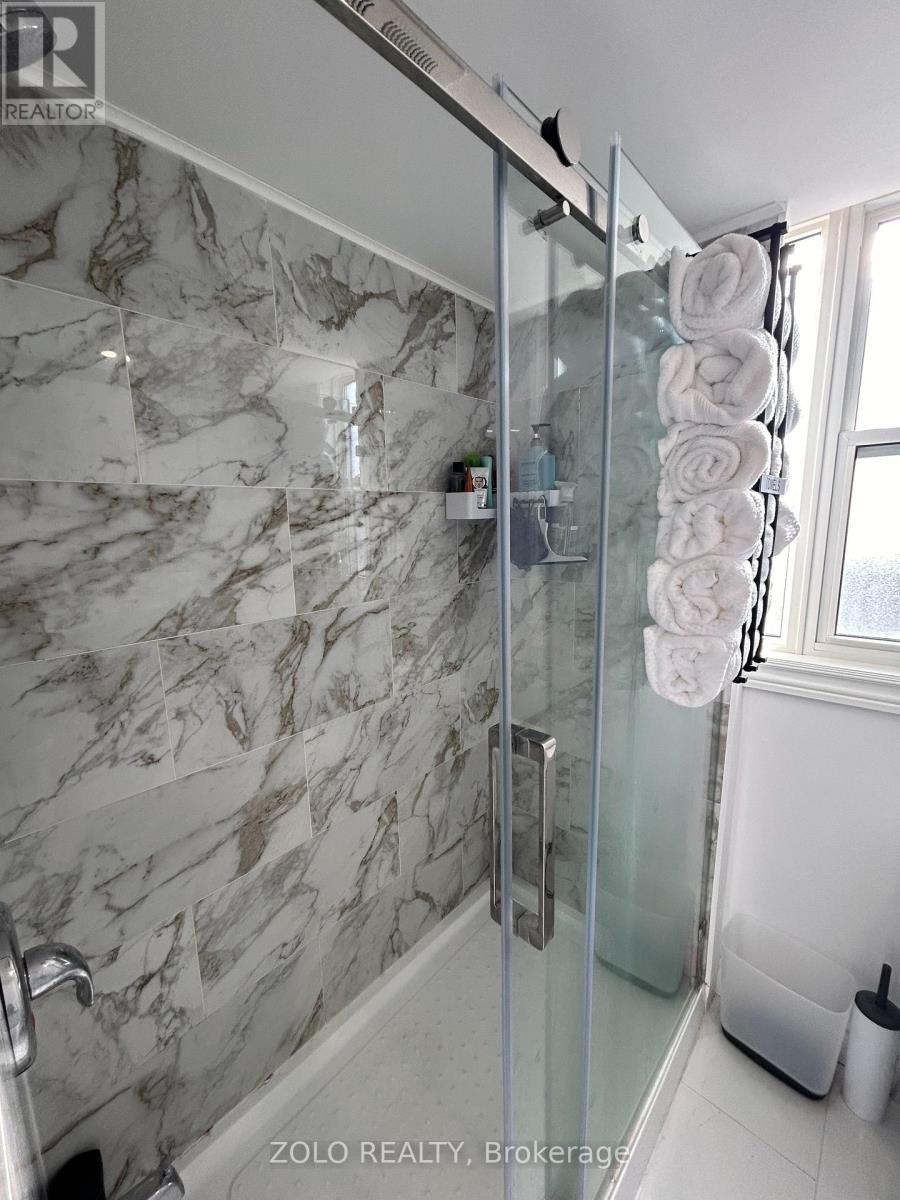 A bathroom with a marble wall and a glass shower door.