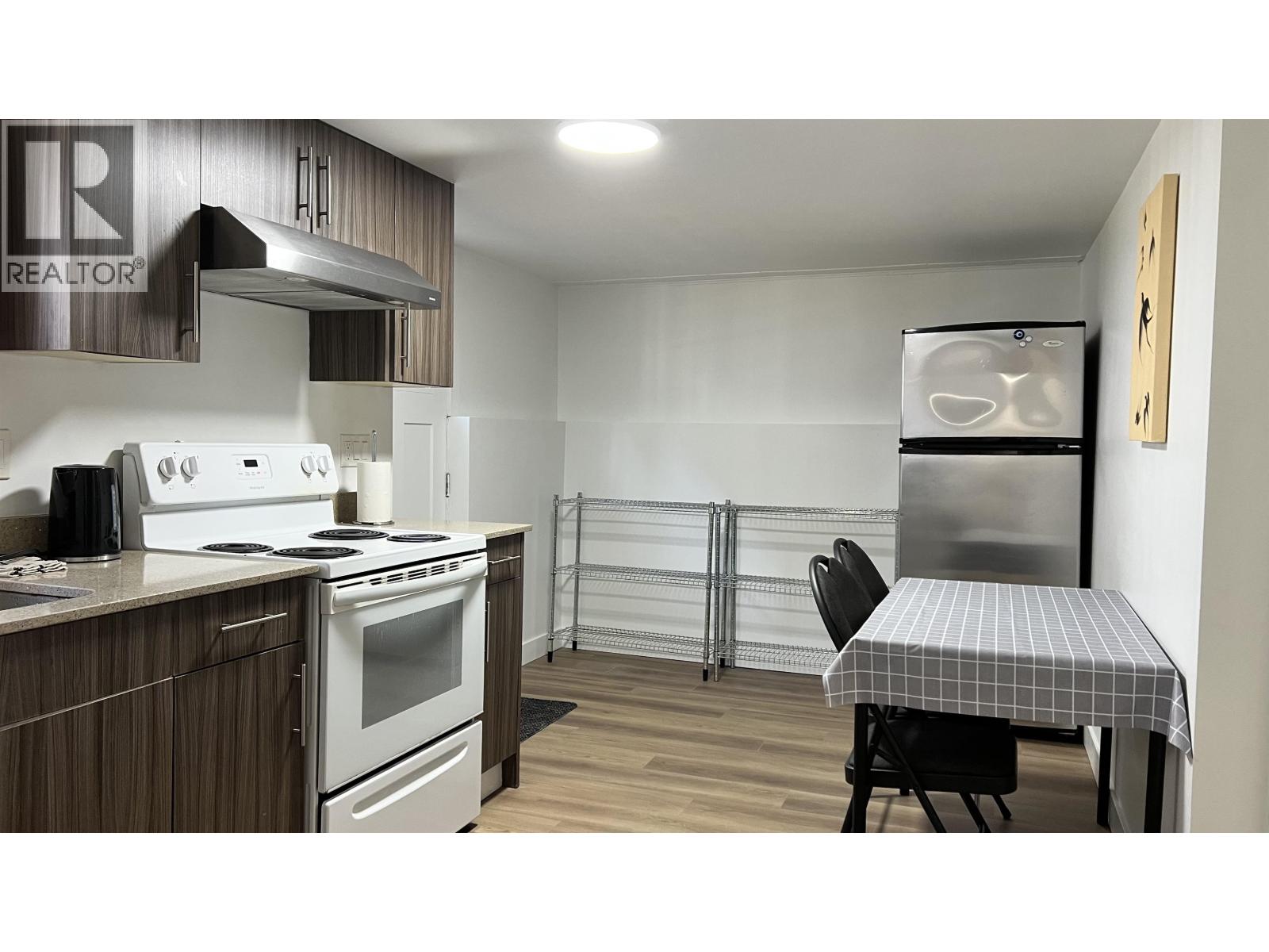 A kitchen with a stove, oven, and a table with a chair.